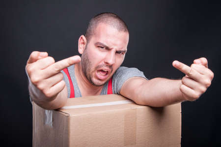 Angry mover guy showing obscene gesture with both hands and yelling on black backgroundの写真素材