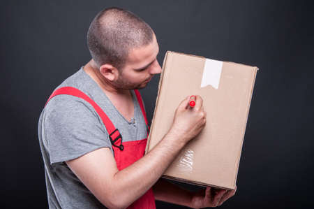 Mover guy writing on box with red marker on black backgroundの写真素材