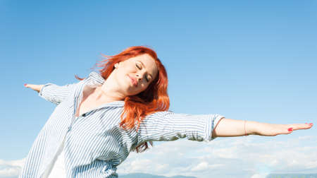 Woman relaxing with arms open enjoying her freedom on a clear sunny dayの写真素材