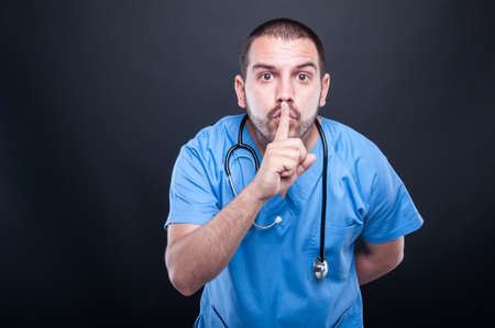 Doctor with stethoscope close-up making listening gesture on black background with copy test spaceの写真素材