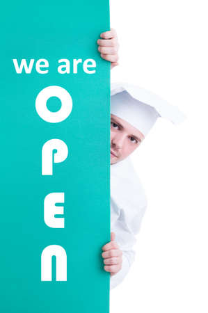 Cook chef standing behind and holding store opening signboard