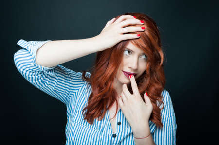 Beauty fashion portrait of  smiling young woman with red hair on dark backgroundの写真素材