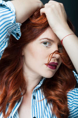 Beauty fashion portrait of caucasian woman with red hair posing on dark background