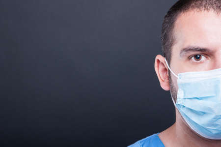 Close-up half face of medic wearing scrubs and sterile mask on black background with copypsace advertising areaの写真素材