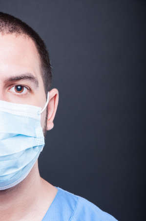 Close-up half face of doctor wearing scrubs and sterile mask on black background with copypsace advertising areaの写真素材