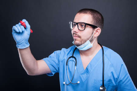Doctor or medic wearing glasses writing on invisible board with red marker on black backgroundの写真素材
