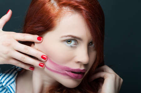 Portrait of beautiful model with smeared lipstick posing sensual on dark backgroundの写真素材