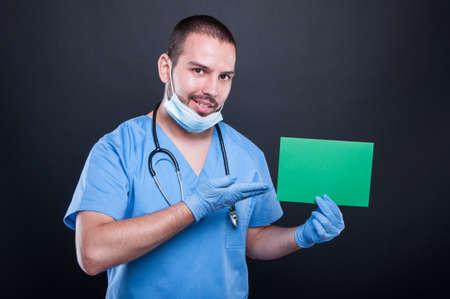 Doctor holding and showing green copypsace card on black background with copy text space