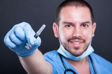 Selective focus of doctor wearing scrubs holding vaccine injection and smiling on black background