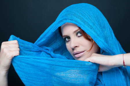 Female model with smokey make up holding blue scarf and looking at the cameraの写真素材