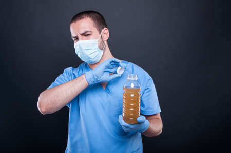 Medic wearing face mask holding bad smelling water like water pollution concept on black background