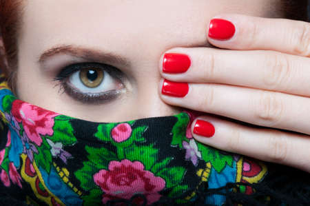 Beauty female showing one eye with smokey makeup at the camera in close-upの写真素材