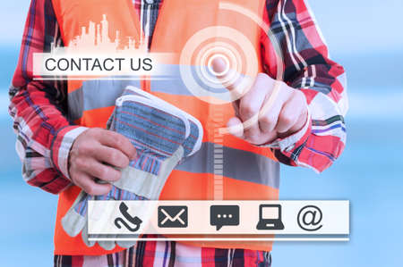 Constructor touching the futuristic interface with contact us icons for professional servicesの写真素材