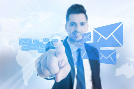 Smiling business man pressing message or email button on futuristic virtual screenの写真素材