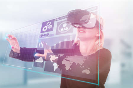 Modern girl with virtual reality or 3d headset touching the futuristic screen with iconsの写真素材