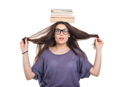 Smart college student with glasses balancing books on top of her headの写真素材