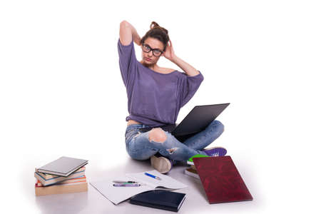 Beautiful young student taking informations from books and online for her homeworkの写真素材