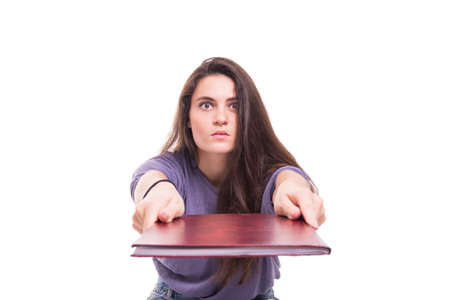 Portrait of girl student girl looking scared while giving book isolated on whiteの写真素材