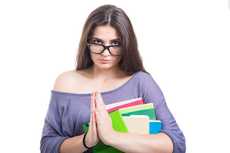 Attractive student girl with lot of books pleading with hands clasped