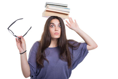 Girl with a pile of books on head preparing for the exam on white backgroundの写真素材