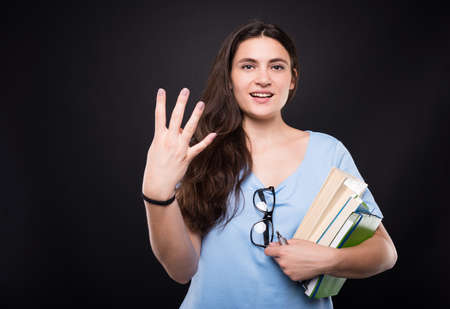 Young beautiful student woman counting four fingers and smilingの写真素材