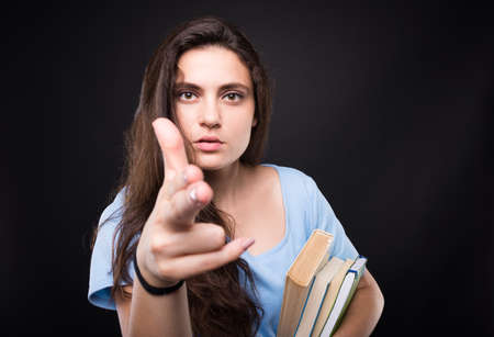 Pretty college woman showing suicide  and shooting you on dark backgroundの写真素材