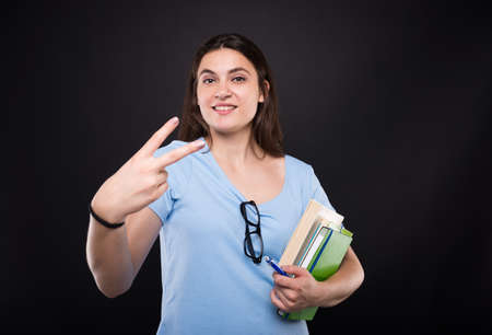 Young girl showing two fingers or counting two looking confident on dark backgroundの写真素材