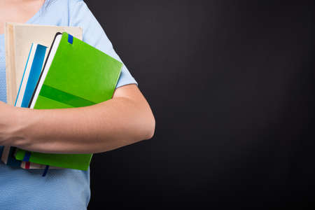 Girl student holding reading books in closeup on black background with copy text spaceの写真素材