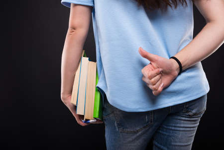 Closeup view of student female rising thumb up behind her back
