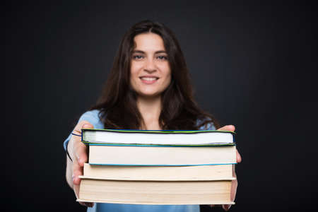 Happy college student holding textbooks and smiling on dark backgroundの写真素材