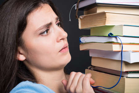 Sad young student holding many books and learning for school exams