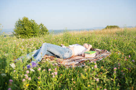 Gorgeous young brunette relaxing outdoors and reading books in summer dayの写真素材