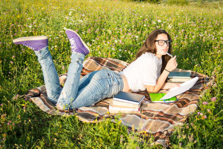 Young girl with book outside in summer day relaxing and reading a novelの写真素材