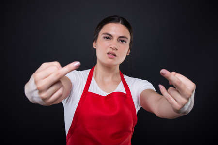 Rude hypermarket seller with red apron showing middle finger with arrogant attitudeの写真素材