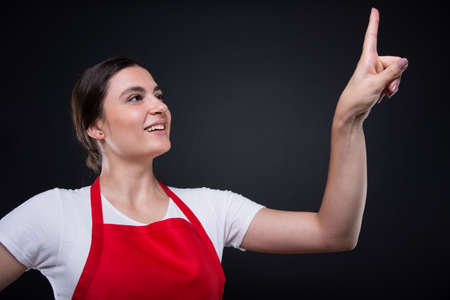 Cheerful girl seller touching the screen with her finger on dark backgroundの写真素材