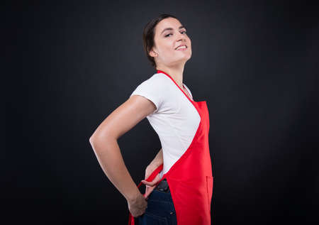 Confident young seller tying up her apron around the waist getting ready for workの写真素材