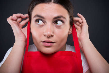 Close-up portrait of girl employee put her apron on preparing to start working in the storeの写真素材