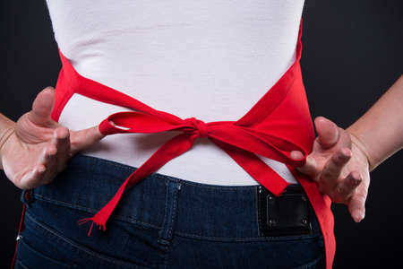 Closeup view of female employee apron knot getting ready for workの写真素材
