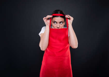 Beautiful brunette seller wearing red supermarket uniform in the storeの写真素材