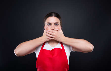 Young female employee covering closed mouth with hands or doing speak no evil gestureの写真素材