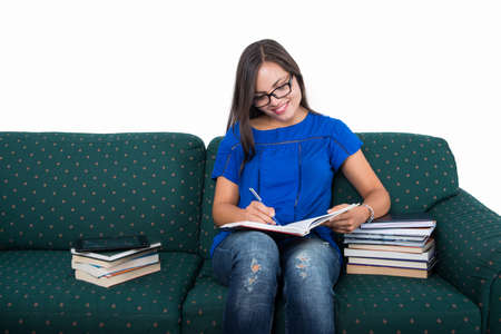 Student girl sitting on couch studying with books around isolated on white background