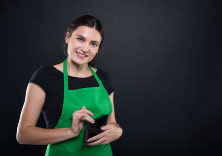 Happy young seller holding her empty wallet after doing shopping and paying with cash money