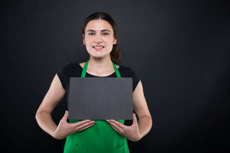 Smiling and friendly female clerk with black paper card and copy spaceの写真素材