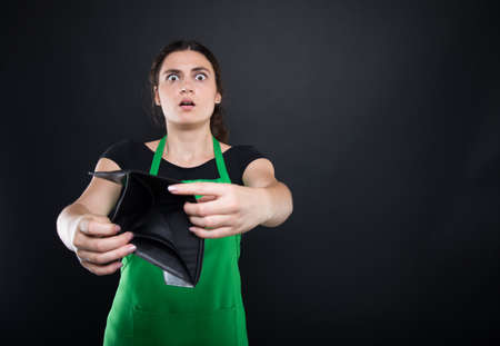 Shocked young woman shows her empty wallet looking stressed and frustratedの写真素材