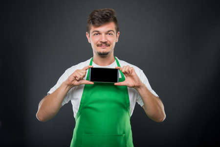 Portrait supermarket employer holding smartphone and smiling on black background