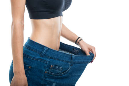 Fit girl holding wearing big size pants like loosing weight concept isolated on white background...