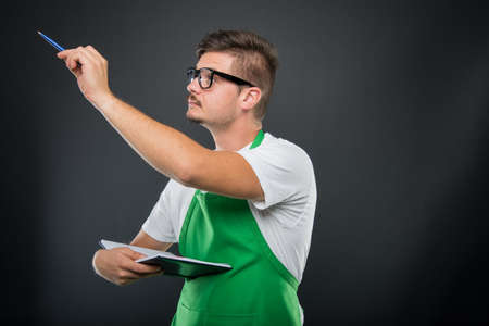 Portrait of supermarket employer holding pen and agenda wearing glasses on black background
