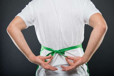 Back view of supermarket employer tying the apron on black backgroundの写真素材