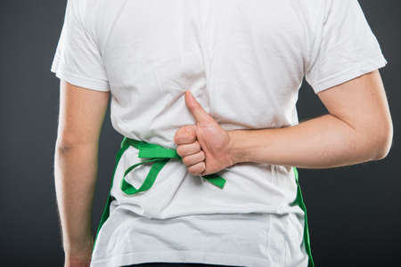 Back view of supermarket employer showing like gesture on black background