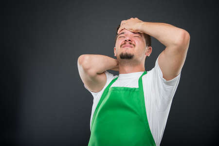 Supermarket employer holding head like hurting on black backgroundの写真素材